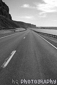 Road Between Lake and Cliff black and white picture